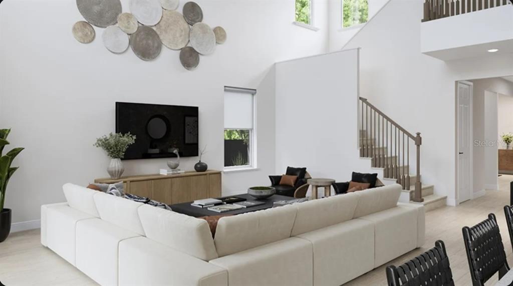 This is a rendering of a living room with a large sectional, staircase, and wall decor — 7895 INTERSTELLAR AVENUE, SARASOTA, FL