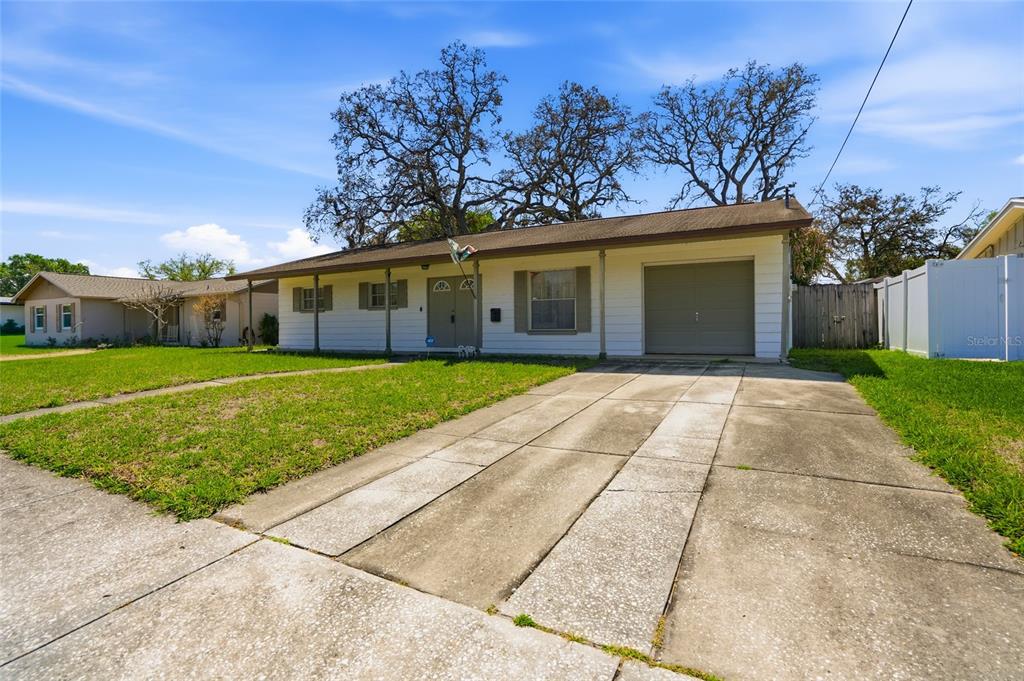 A single-story house with white siding, a concrete driveway, and a front-facing garage — 3312 W BURKE ST, TAMPA, FL