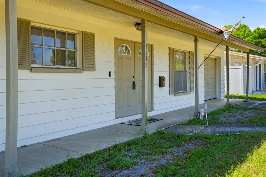 A white house exterior features a covered porch, a front door, and a garage door — 3312 W BURKE ST, TAMPA, FL
