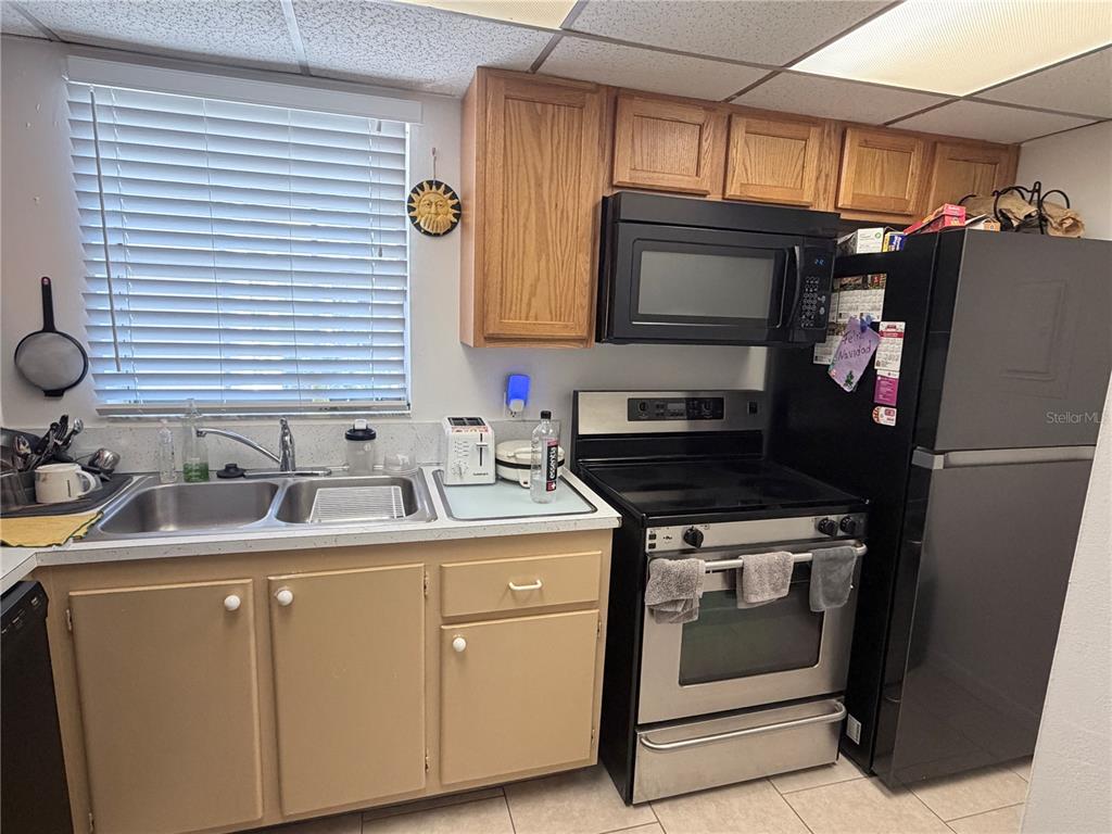A kitchen features light-colored cabinets, stainless steel appliances, and a window with white blinds — 2727 75TH STREET W UNIT 7A15, BRADENTON, FL