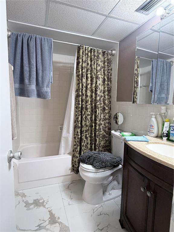 A bathroom features a white tub, a patterned shower curtain, a toilet, and a vanity — 2727 75TH STREET W UNIT 7A15, BRADENTON, FL