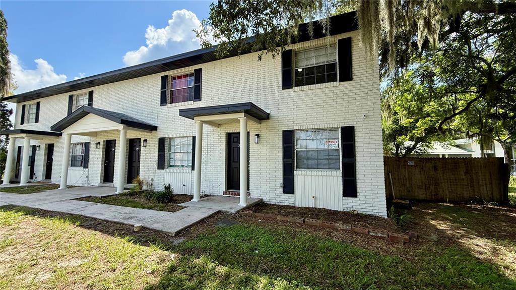 A two-story white brick apartment building with black shutters and covered entryways — 202 CENTURY BOULEVARD UNIT D, AUBURNDALE, FL