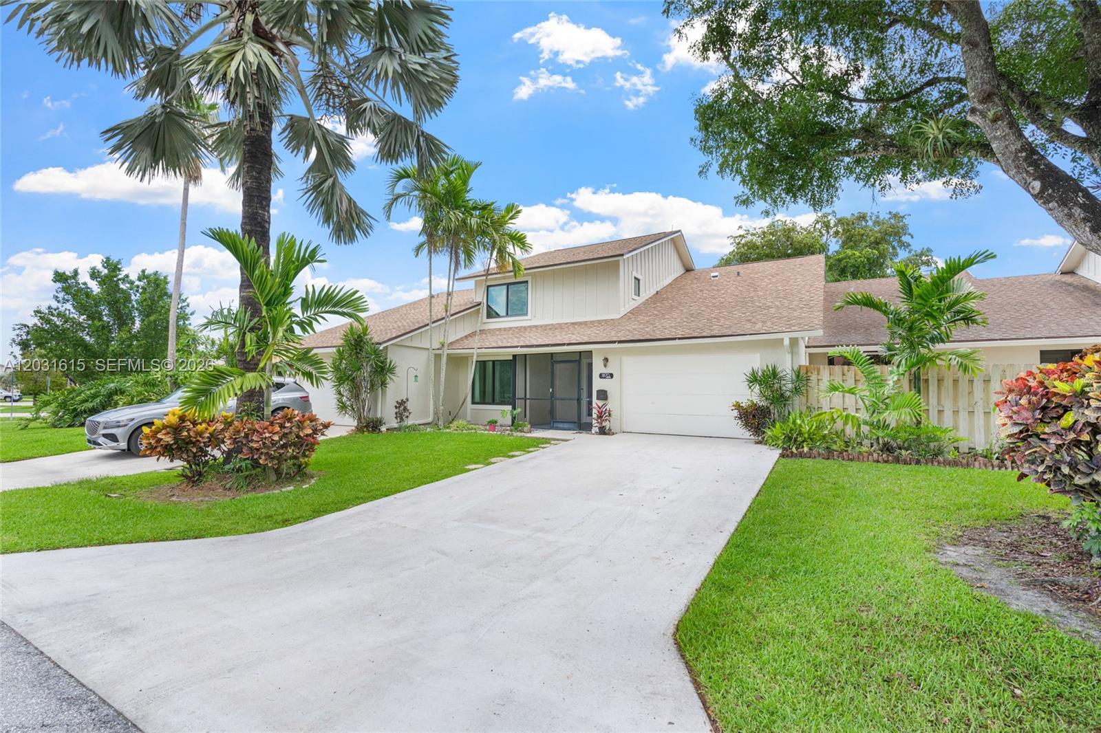 A two-story house with a white garage, concrete driveway, and palm trees in the yard — 11870 Donlin Dr, Wellington FL 33414, WELLINGTON, FL