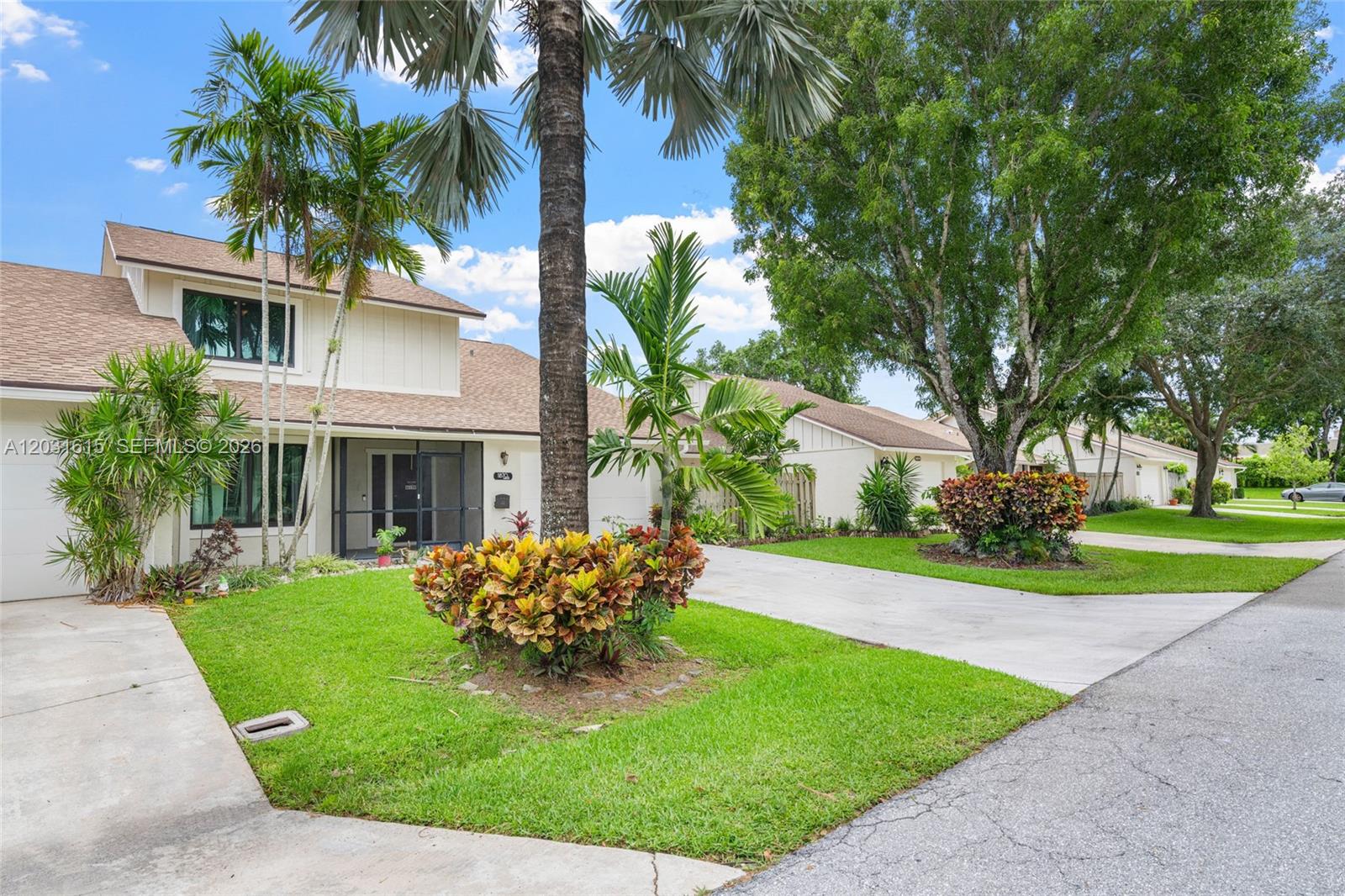 A two-story house with a screened entryway, palm trees, and a concrete driveway — 11870 Donlin Dr, Wellington FL 33414, WELLINGTON, FL