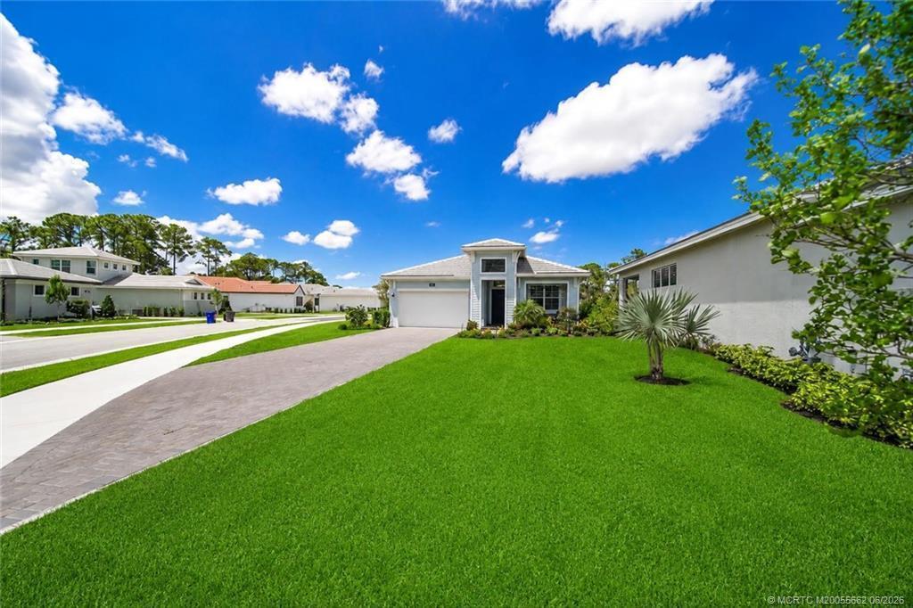 A single-story house with a paved driveway and green lawn under a blue sky — 6941 SE Haven Lane, Stuart FL 34997, STUART, FL