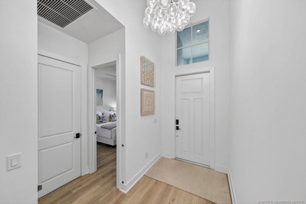 A blue front door with a transom window opens onto a brick-paved covered porch — 6941 SE Haven Lane, Stuart FL 34997, STUART, FL