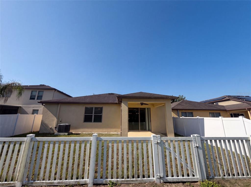 The exterior rear view of a house features a covered patio and a white fence — 1857 TRILLIUM BOULEVARD, BROOKSVILLE, FL