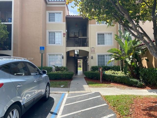 A light-colored multi-story apartment building features a central breezeway and a parked silver car — 2051 Renaissance Blvd # 206, Miramar FL 33025, MIRAMAR, FL