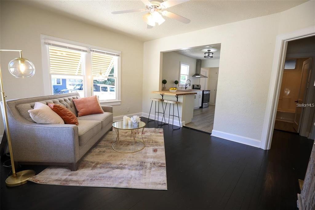 A living room with dark wood floors, a grey sofa, and a kitchen pass-through window — 2521 4TH STREET S, ST PETERSBURG, FL