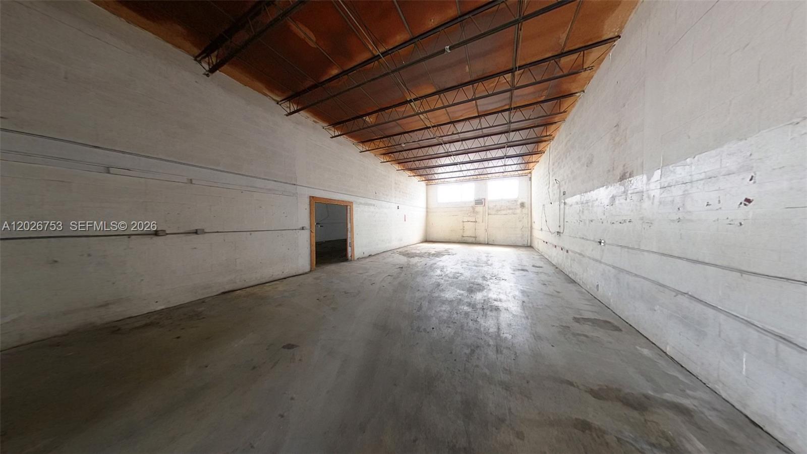 An empty industrial warehouse space features white concrete walls, a concrete floor, and exposed trusses — 1055 SE 9th Ct # 65, Hialeah FL 33010, HIALEAH, FL