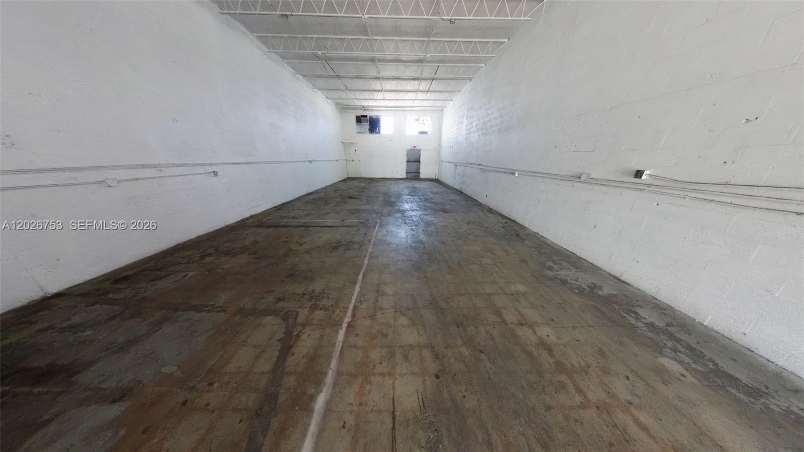 An empty, rectangular warehouse space features white painted block walls and a concrete floor — 1055 SE 9th Ct # 65, Hialeah FL 33010, HIALEAH, FL