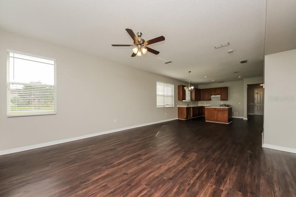 An open-concept living and kitchen area features dark wood-look flooring and a ceiling fan — 917 ANCHORAGE LANE, KISSIMMEE, FL