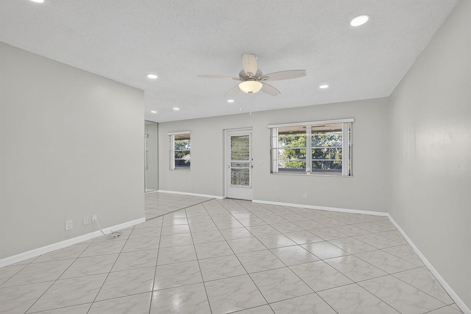 An empty room with light gray walls, white tile flooring, a ceiling fan, and windows — 149 Hastings I, West Palm Beach FL 33417, WEST PALM BEACH, FL