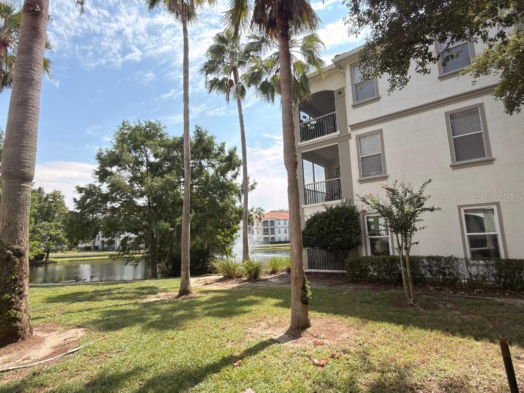 Exterior view of a multi-story apartment building with palm trees and a pond — 2525 MAITLAND CROSSING WAY UNIT 202, ORLANDO, FL