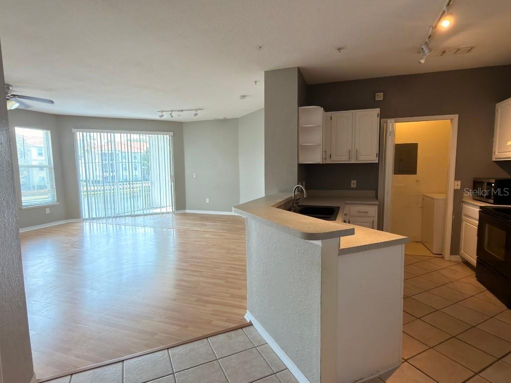 A kitchen with a breakfast bar overlooks a living area with light wood-look flooring — 2525 MAITLAND CROSSING WAY UNIT 202, ORLANDO, FL