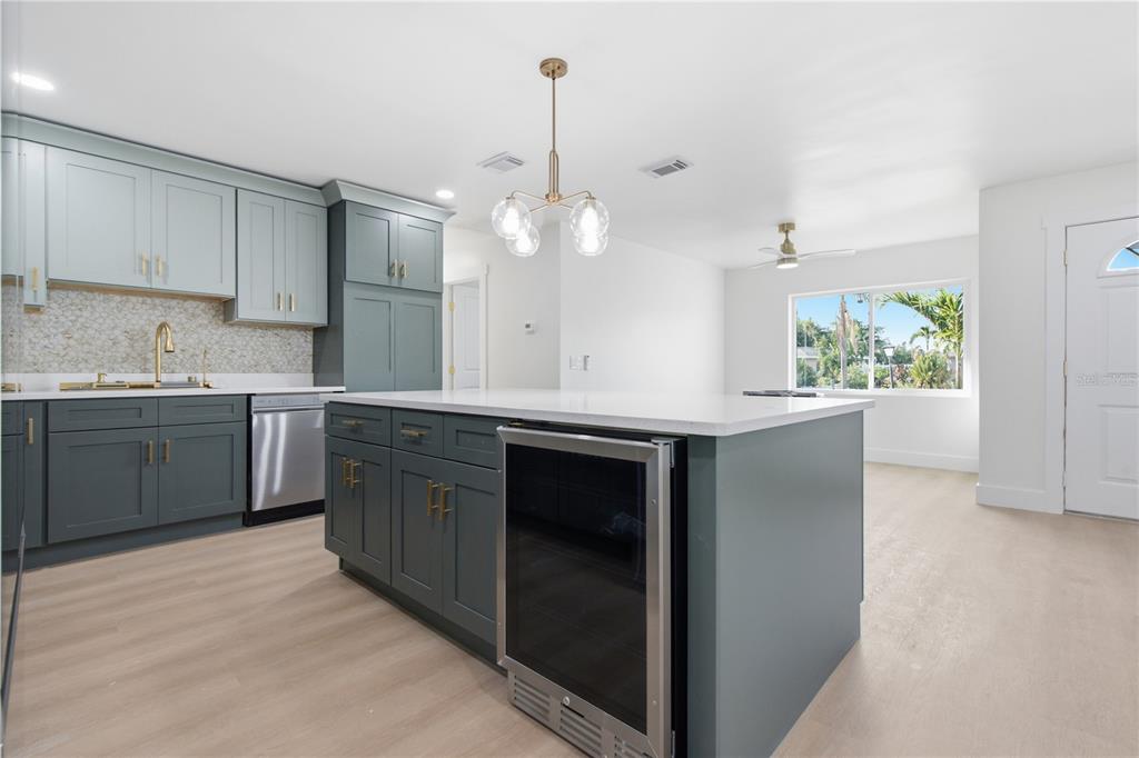 A kitchen features two-toned blue cabinetry, a white quartz island, and light wood-look flooring — 9460 TREASURE LANE NE, ST PETERSBURG, FL