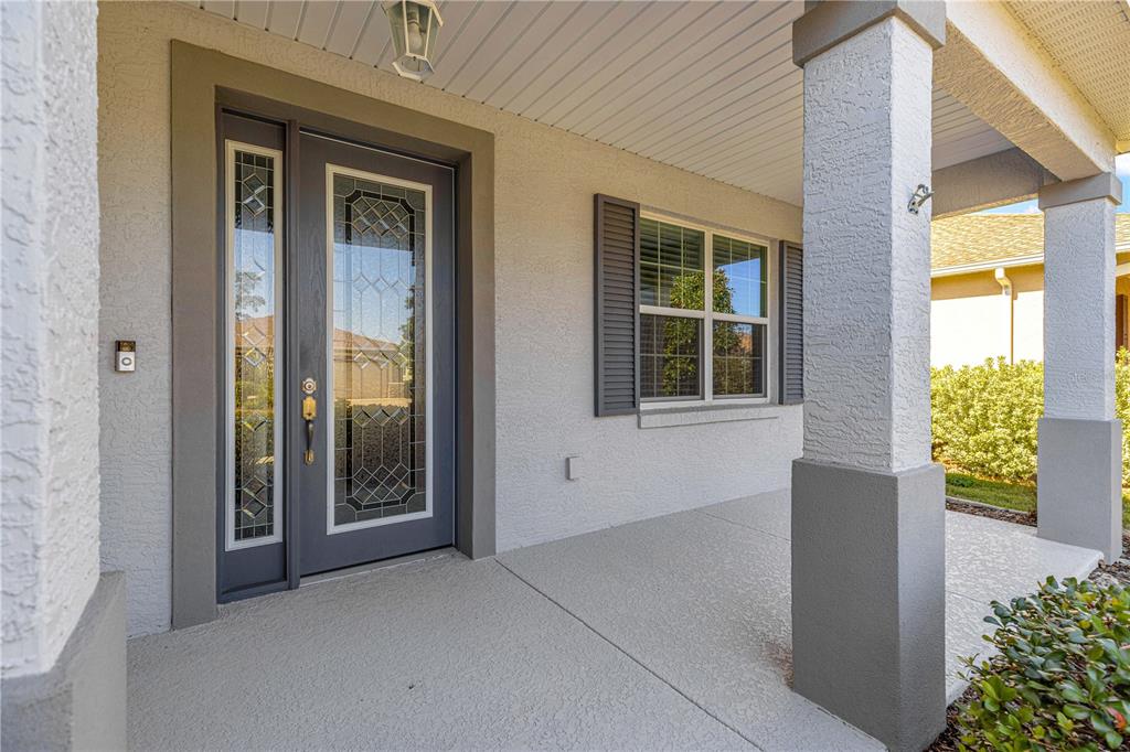 A covered front porch features a gray door with glass inserts and a concrete floor — 8546 SW 79TH AVENUE, OCALA, FL