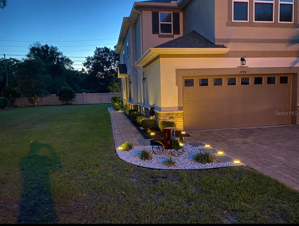 A side view of a house exterior at dusk featuring a paved walkway and landscaping — 3778 BRIGHTON PARK CIRCLE, ORLANDO, FL