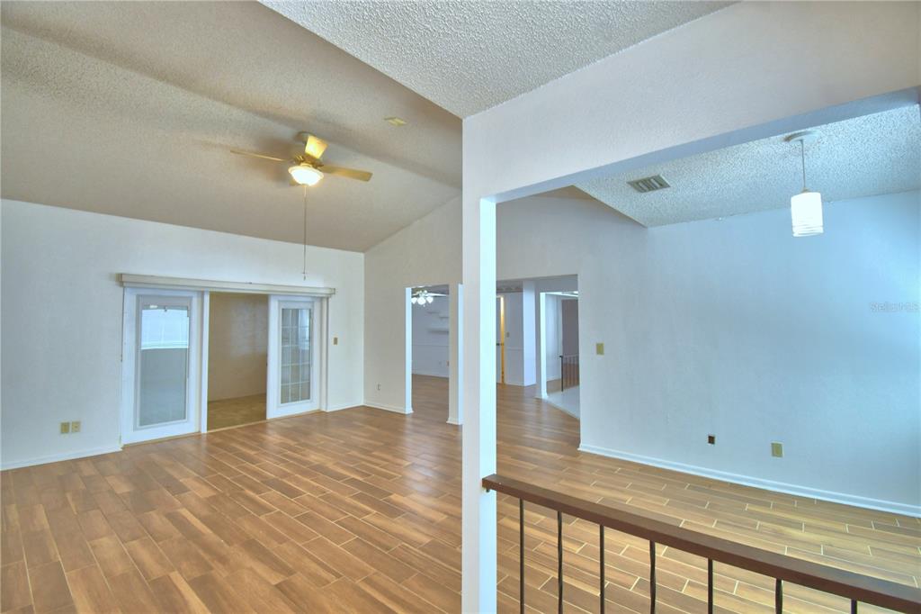 An interior view of a living area featuring vaulted ceilings, wood-look flooring, and French doors — 447 SAN JOSE DRIVE, WINTER HAVEN, FL