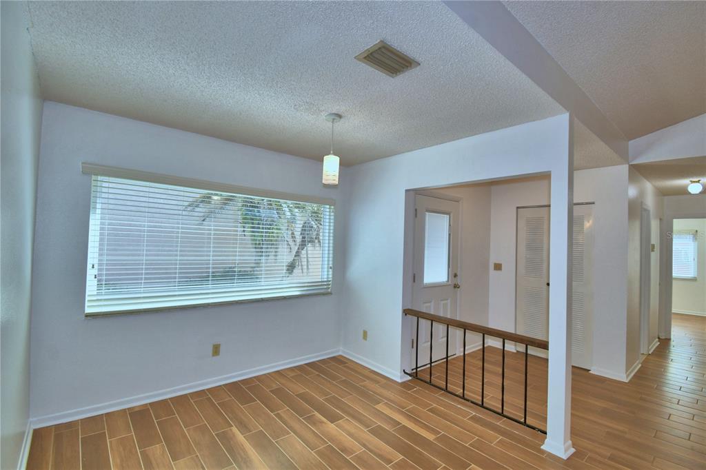 A dining area with wood-look tile flooring, a large window, and a metal stair railing — 447 SAN JOSE DRIVE, WINTER HAVEN, FL