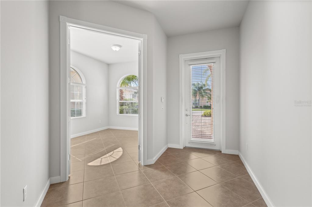 A tiled hallway leads to a room with arched windows and a glass-paned exterior door — 13180 IPOLITA STREET, VENICE, FL