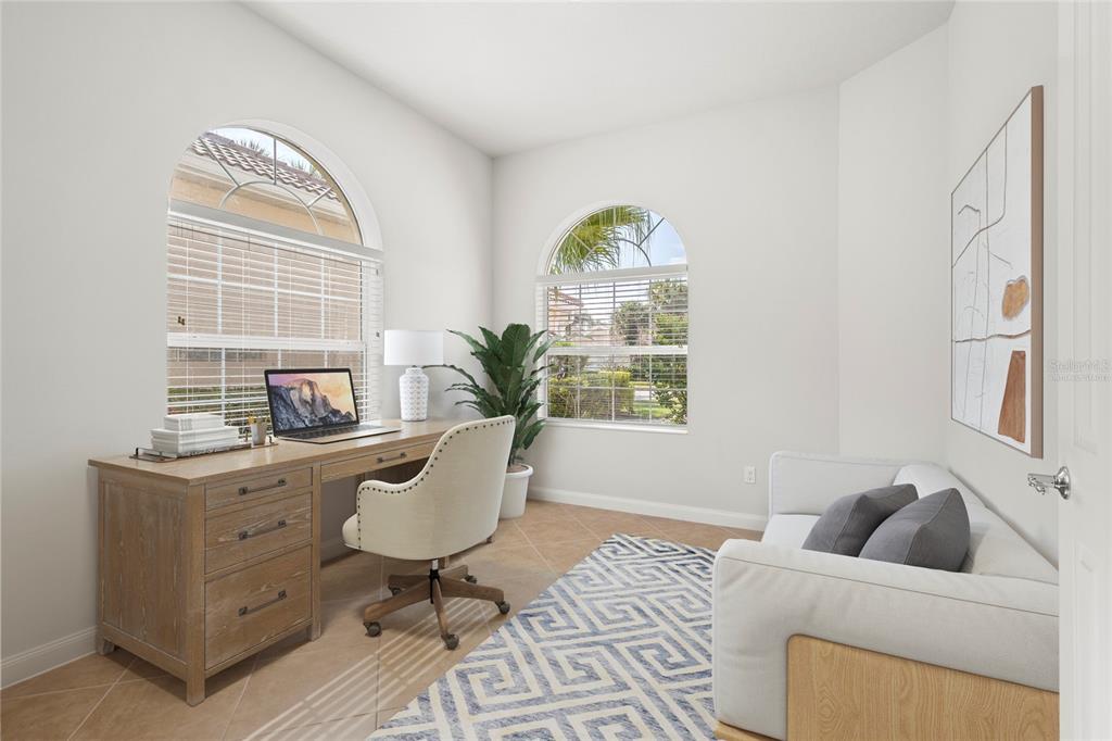 A home office features a wooden desk, an upholstered chair, a sofa, and arched windows — 13180 IPOLITA STREET, VENICE, FL