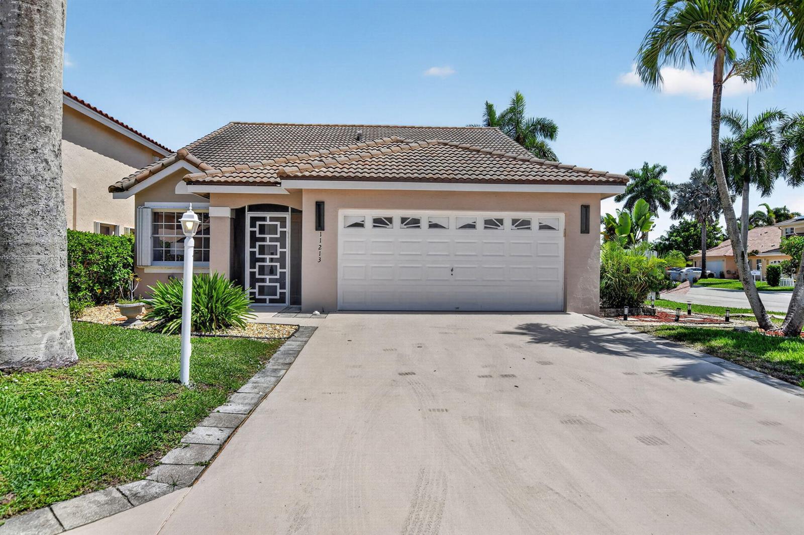 A single-story house with a beige stucco exterior, a tile roof, and a two-car garage — 11213 Jasmine Hill Circle, Boca Raton FL 33498, BOCA RATON, FL