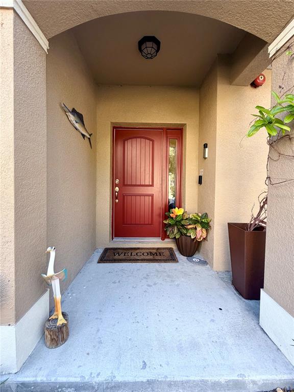 A red front door is centered under a covered entryway with a concrete floor — 849 CALLISTA CAY LOOP, TARPON SPRINGS, FL