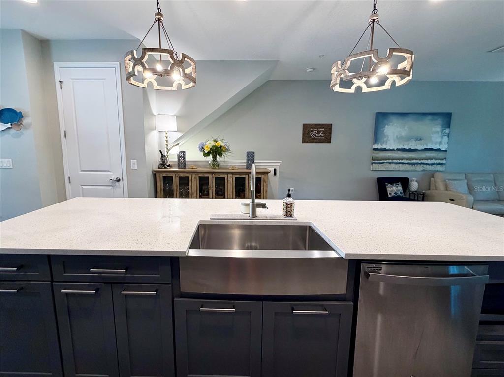A kitchen island with a farmhouse sink and dark cabinets sits before a dining area — 849 CALLISTA CAY LOOP, TARPON SPRINGS, FL