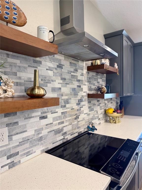 A kitchen features a stainless steel range hood, floating wood shelves, and a mosaic backsplash — 849 CALLISTA CAY LOOP, TARPON SPRINGS, FL