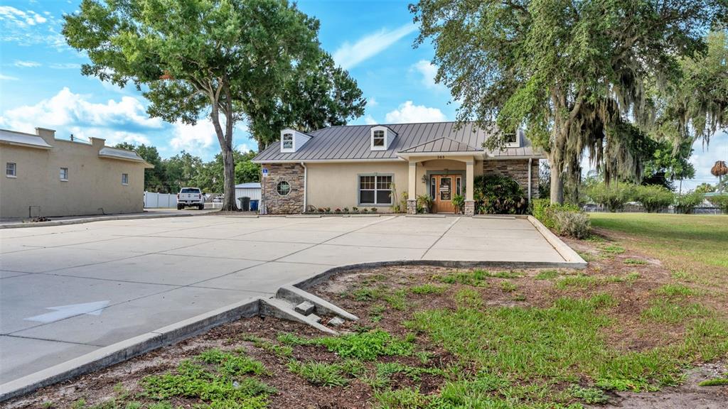 A single-story commercial building with a metal roof and stone facade faces a parking lot — 565 W MAIN STREET, BARTOW, FL