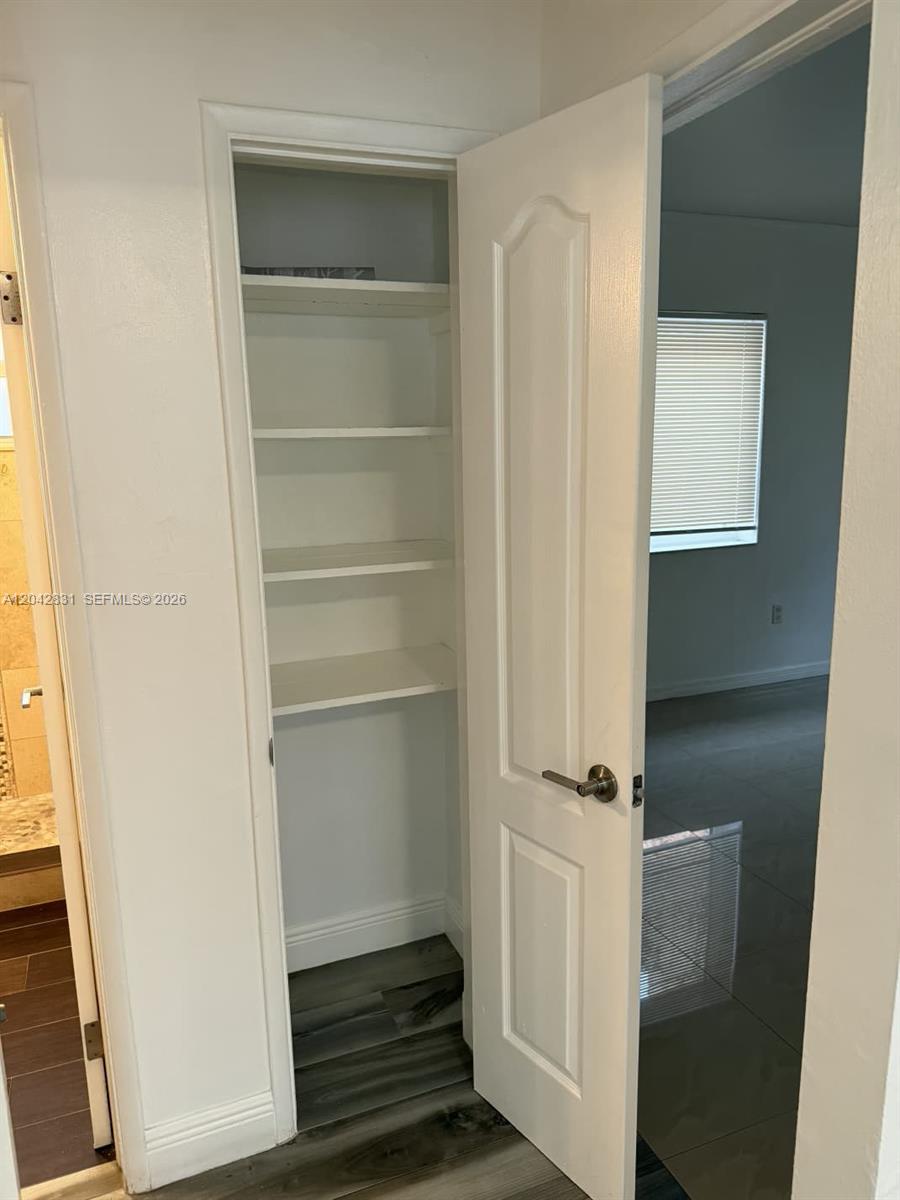 A white door opens to reveal a narrow closet with multiple built-in shelves — 3115 NW 23rd Ave # 0, Miami FL 33142, MIAMI, FL