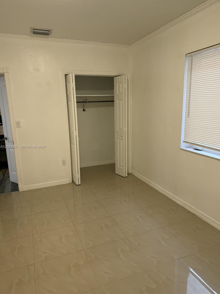 This room features light-colored tile flooring, white walls, and an open closet with bi-fold doors — 3115 NW 23rd Ave # 0, Miami FL 33142, MIAMI, FL