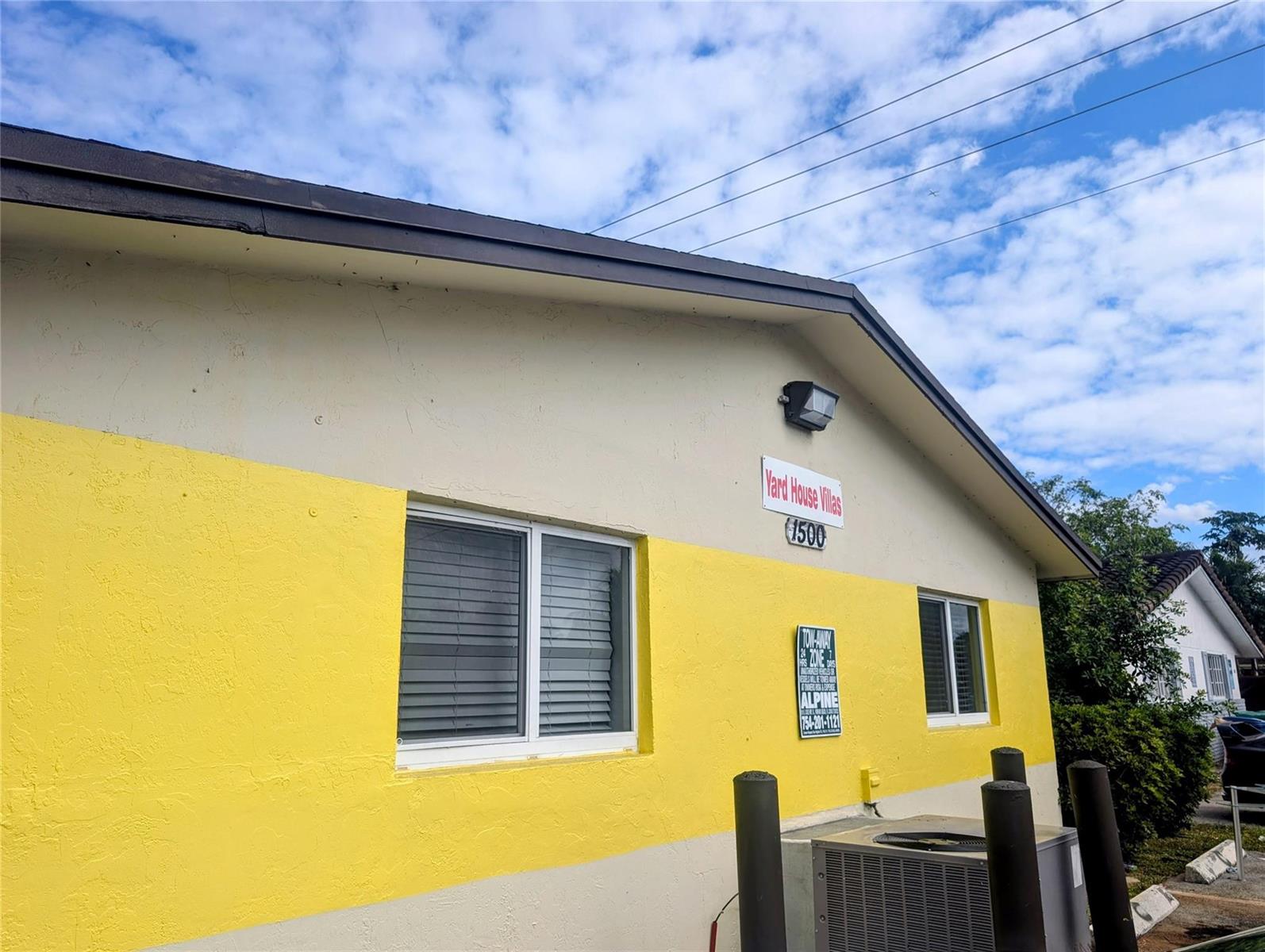 The exterior of a building features yellow and beige stucco walls with two windows — 1500 NW 58th Terrace, Sunrise FL 33313, SUNRISE, FL