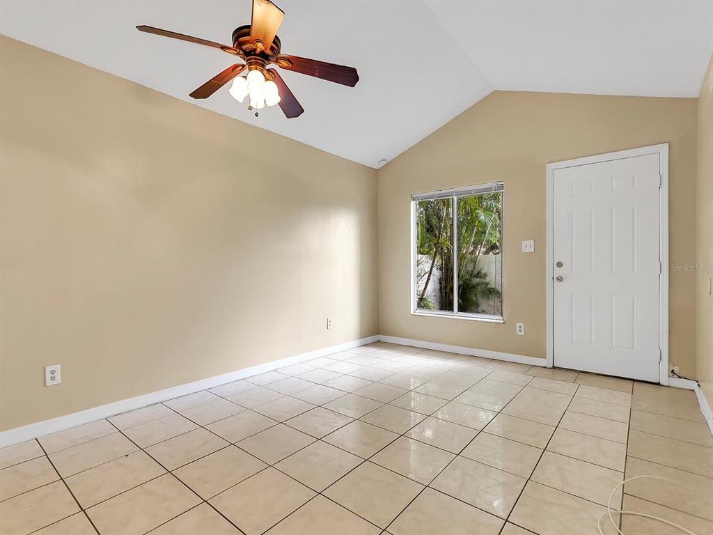 An empty room with beige walls, tile flooring, a ceiling fan, and a white door — 10425 RIVA RIDGE TRAIL, ORLANDO, FL