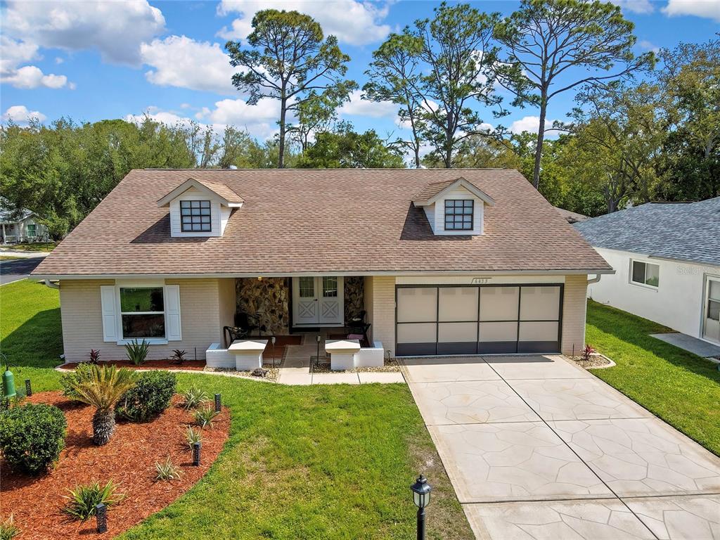 A single-story house with a brown shingled roof, two dormer windows, and a concrete driveway — 6433 LOST TREE LANE, SPRING HILL, FL