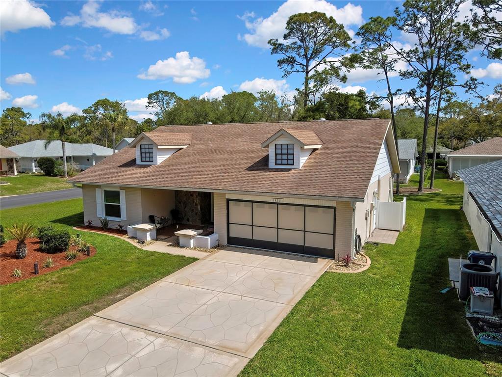 An aerial view of a single-story house with a brown roof, dormers, and a garage — 6433 LOST TREE LANE, SPRING HILL, FL