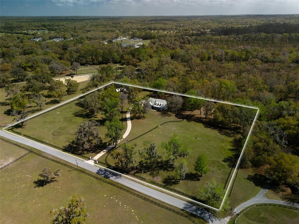 An aerial view shows a house on a fenced, tree-filled lot near a road — 8535 NW 136TH AVENUE ROAD, OCALA, FL