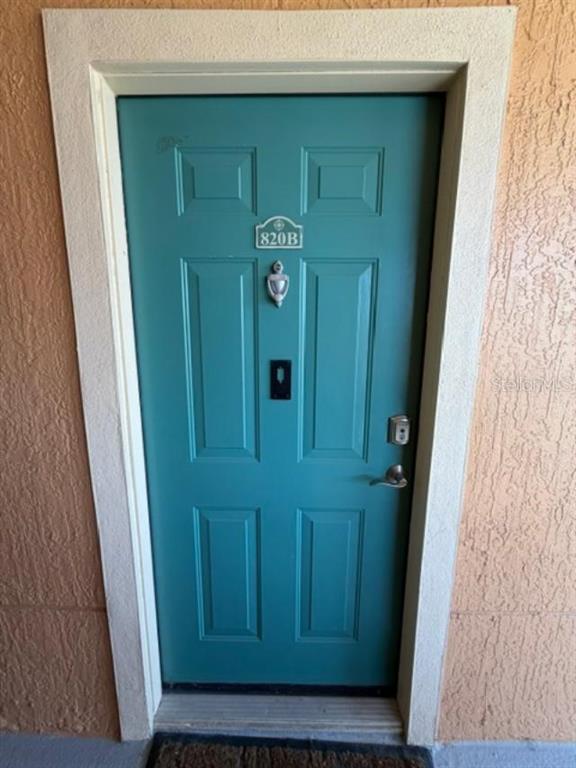 A teal-colored front door with a silver knocker and a unit number sign — 2733 VIA CIPRIANI UNIT 820B, CLEARWATER, FL