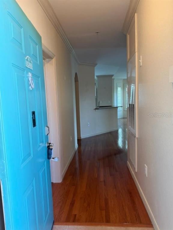 An entryway with a bright blue door leads into a hallway with hardwood floors — 2733 VIA CIPRIANI UNIT 820B, CLEARWATER, FL