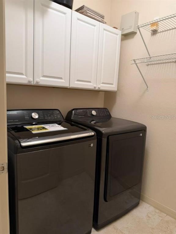 A laundry room features dark gray Samsung appliances, white upper cabinets, and wire wall shelving — 2733 VIA CIPRIANI UNIT 820B, CLEARWATER, FL