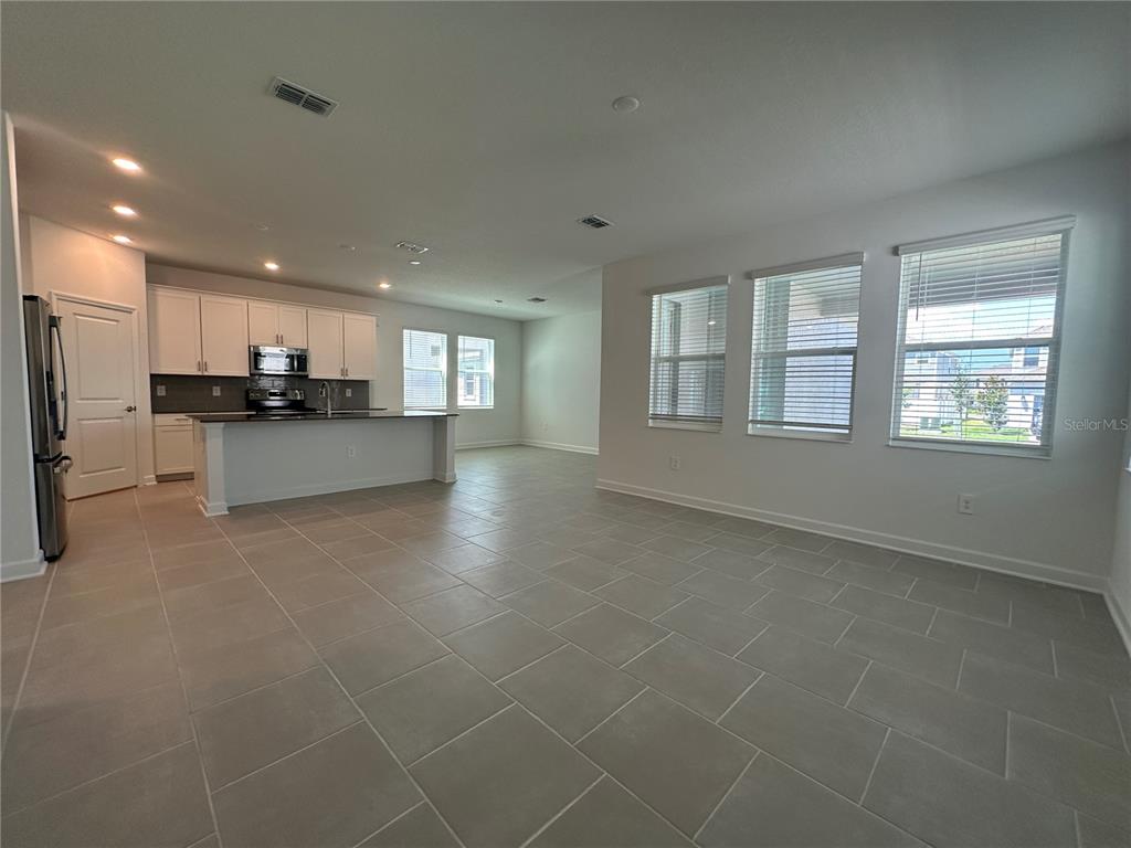 An open-concept kitchen and living area features white cabinets, a kitchen island, and tile flooring — 3052 PARK VALE ROAD, ST CLOUD, FL