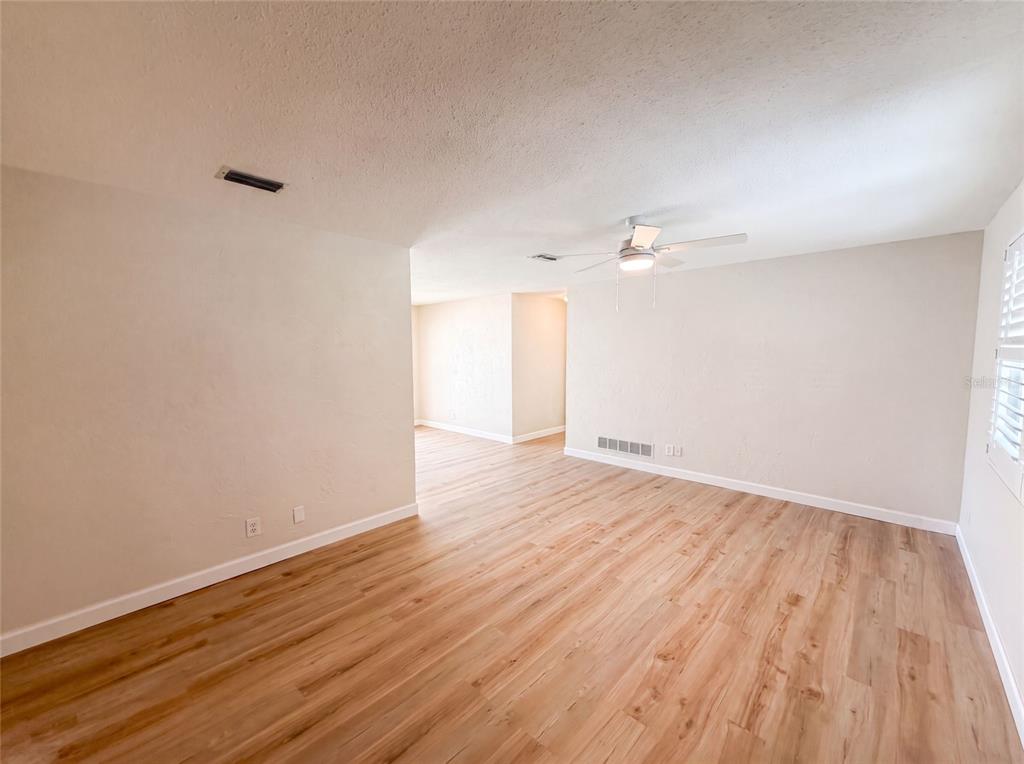 An empty room with light wood-look flooring, beige walls, and a ceiling fan — 624 SHERMAN ROAD, SOUTH DAYTONA, FL