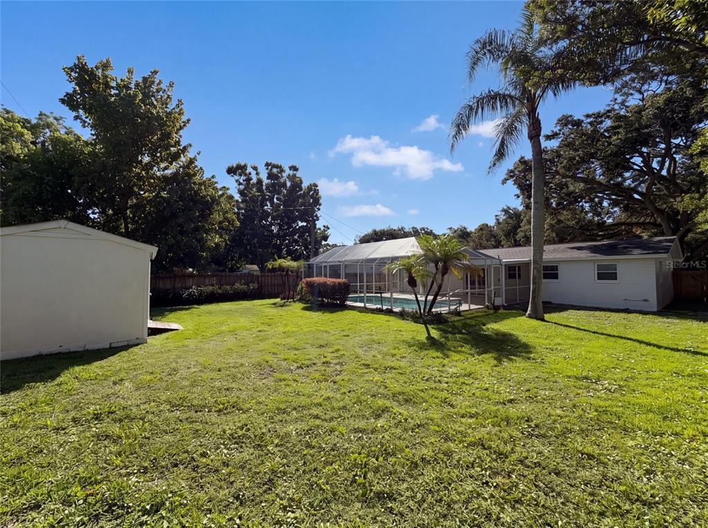 A backyard features a swimming pool with a screen enclosure, a shed, and mature trees — 624 SHERMAN ROAD, SOUTH DAYTONA, FL