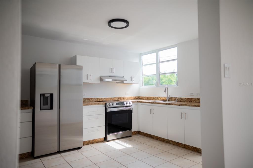 A kitchen features white cabinets, stainless steel appliances, and tan granite countertops — 29 CALLE BASILIO CATALA UNIT 210, GUAYNABO, PR