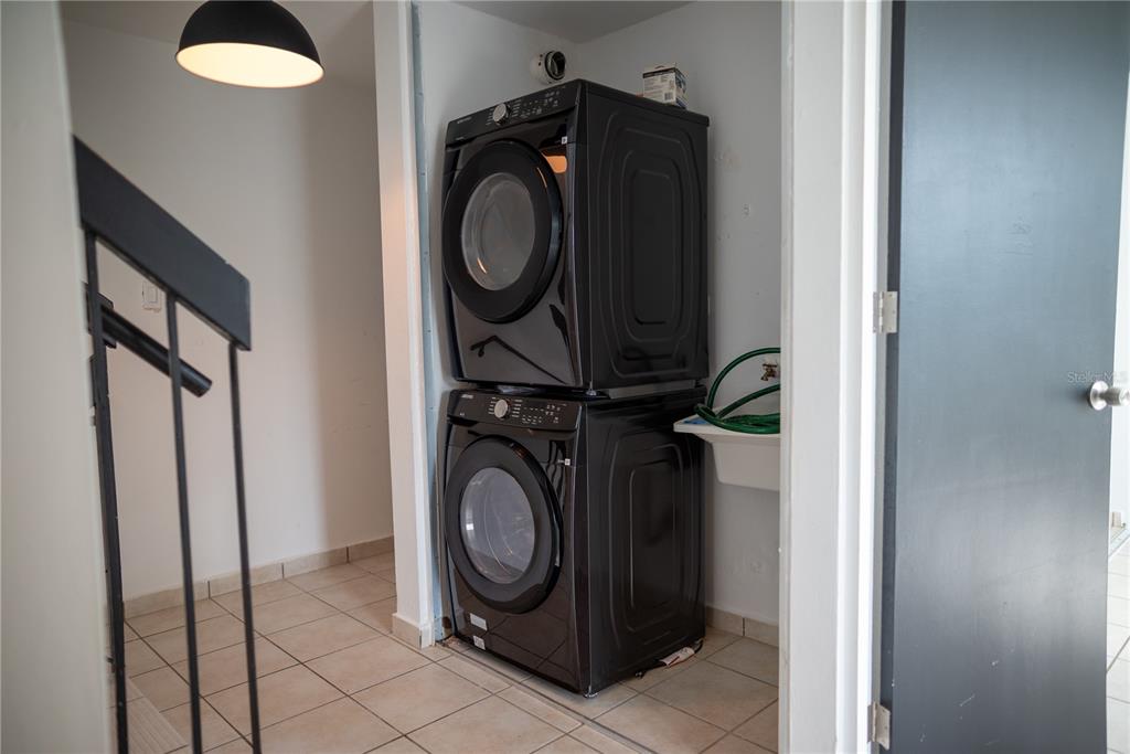 A stacked black washer and dryer set sits in a tiled laundry closet — 29 CALLE BASILIO CATALA UNIT 210, GUAYNABO, PR
