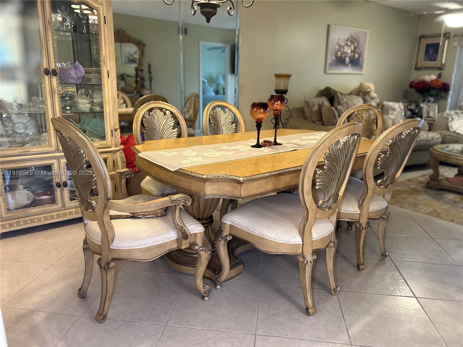 A dining room features a wooden table with ornate chairs and a matching display cabinet — 9802 Marina Blvd # 125, Boca Raton FL 33428, BOCA RATON, FL