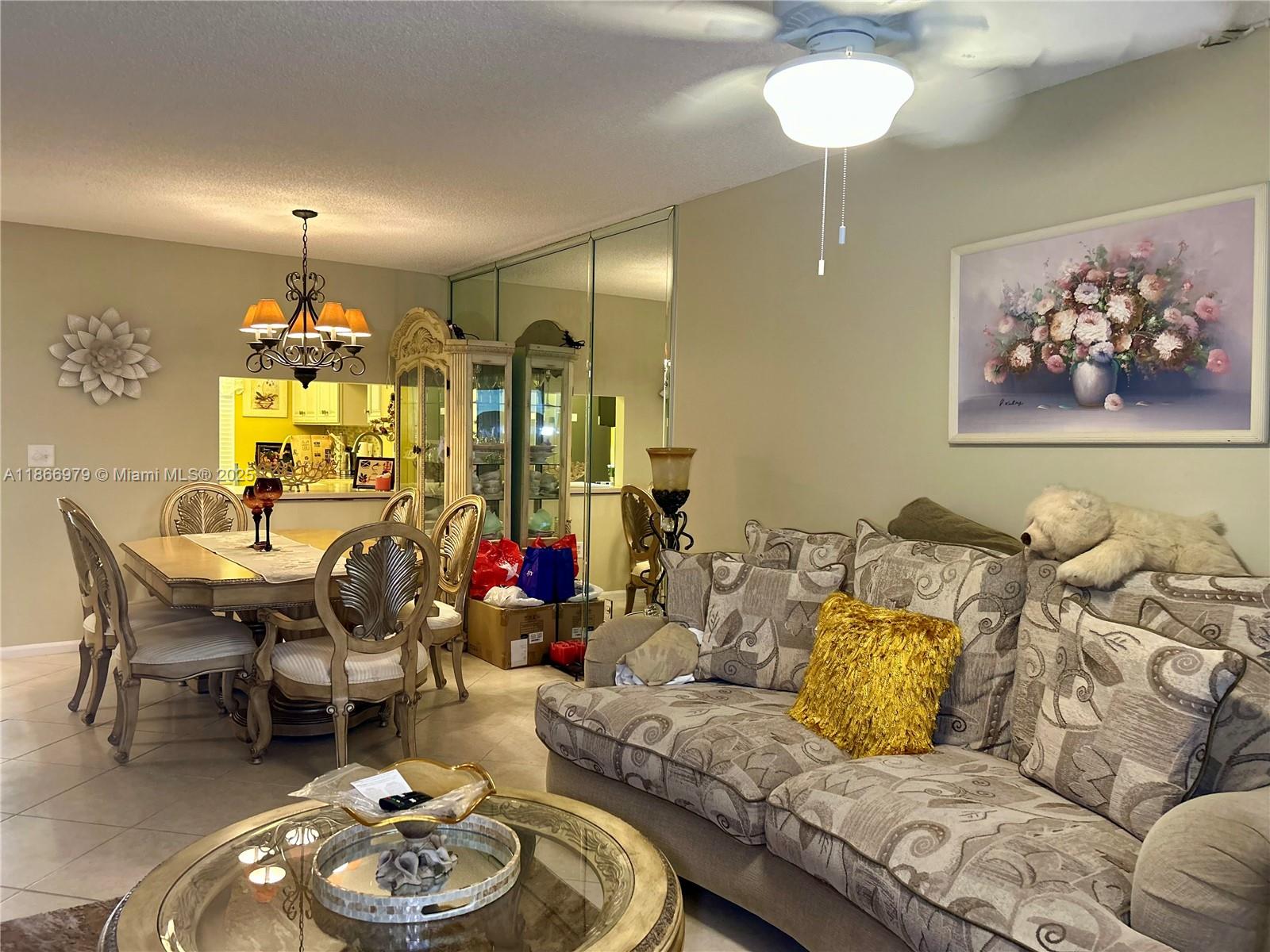 A living and dining area features a patterned sofa, glass coffee table, and mirrored walls — 9802 Marina Blvd # 125, Boca Raton FL 33428, BOCA RATON, FL