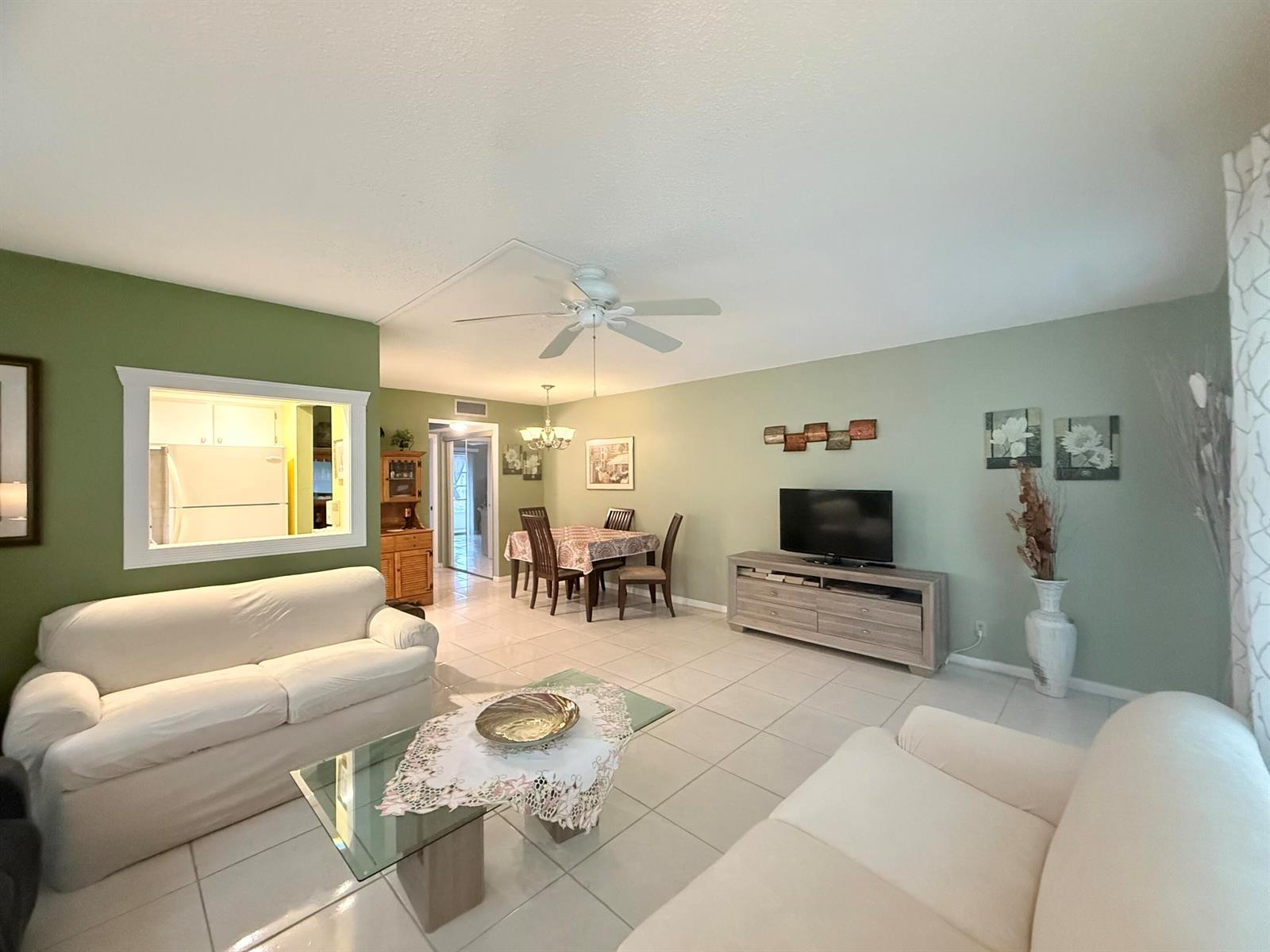 A living room and dining area with light green walls, white tile floors, and white sofas — 204 Durham D # 204, Deerfield Beach FL 33442, DEERFIELD BEACH, FL