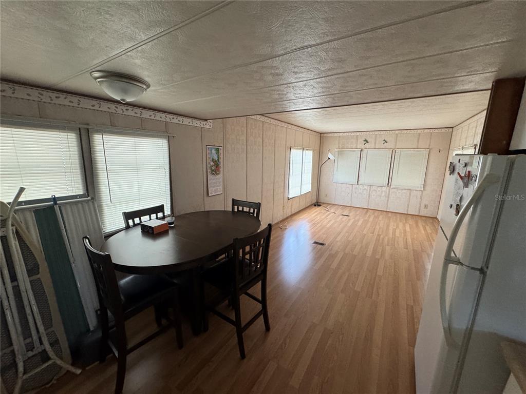 A dining area with wood-look flooring, paneled walls, and a round table with chairs — 1843 SHADY COVE DRIVE, HOLIDAY, FL